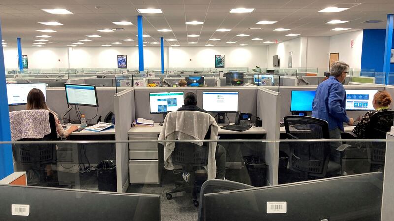 Workers at a Medicaid call center review information regarding eligibility determinations on...