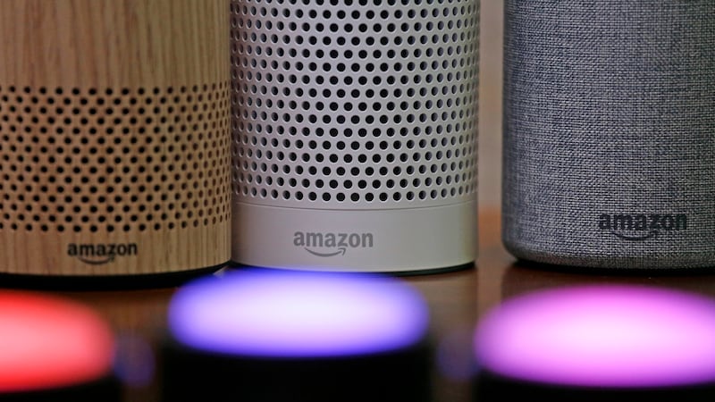 FILE - Amazon Echo and Echo Plus devices, behind, sit near illuminated Echo Button devices...